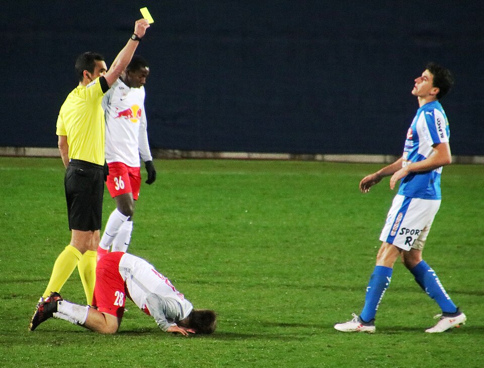 Árbitro mostrando tarjeta amarilla en un partido disputado