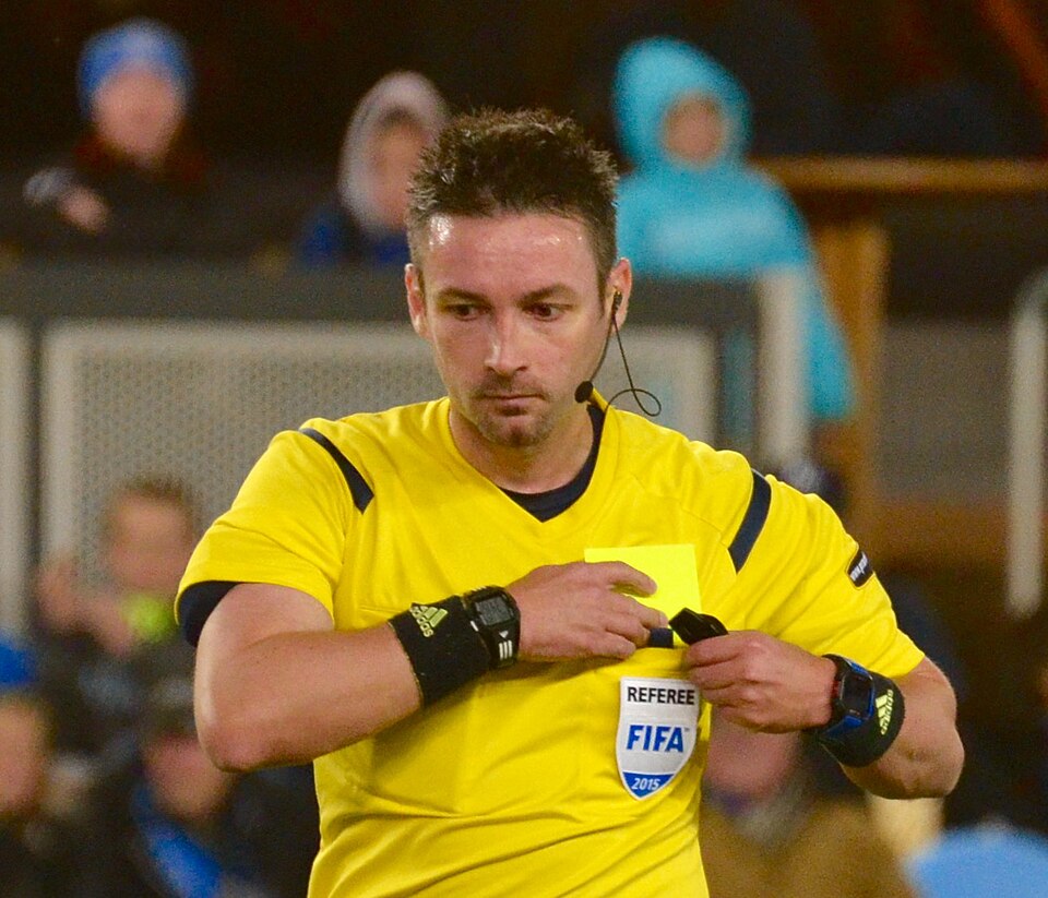 Árbitro mostrando tarjeta amarilla en un clásico