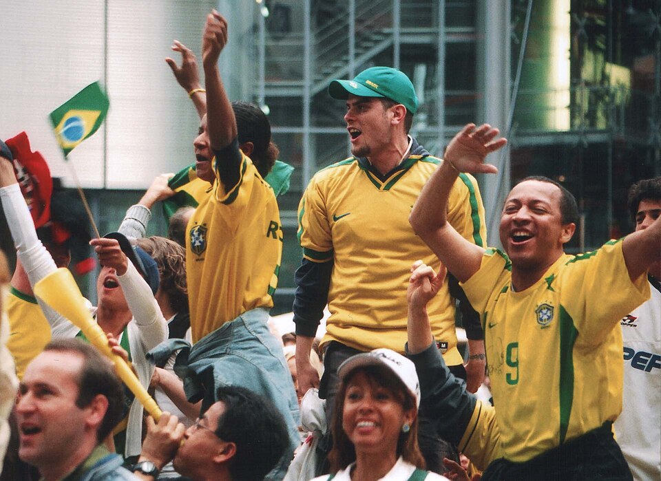 Hinchas brasileños celebrando con banderas en una tribuna