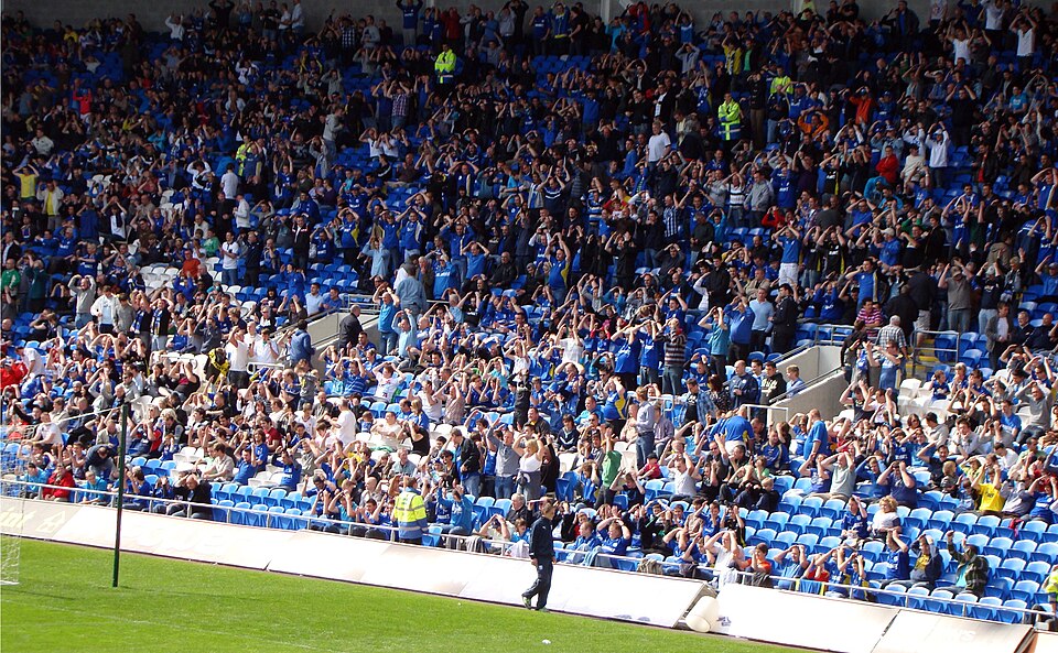 Aficionados viendo fútbol en un bar deportivo durante la noche